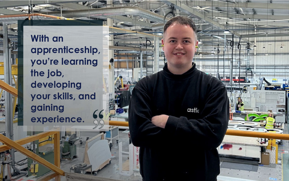 Smiling person in a black "astle" sweater stands confidently in a modern factory setting. Prominent text reads, "With an apprenticeship, you’re learning the job, developing your skills, and gaining experience." Industrial equipment and tools in the background highlight a high-tech manufacturing environment.