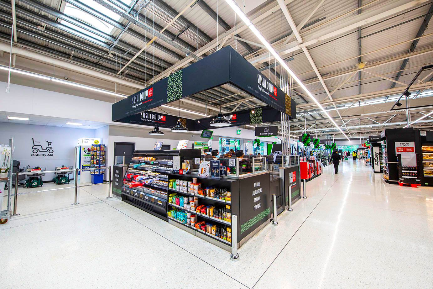 A supermarket aisle features a coffee shop with snacks, drinks, and a seating area.