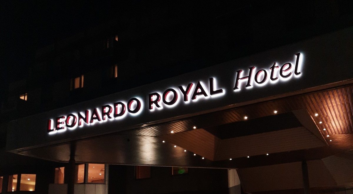 Illuminated sign reads "Leonardo Royal Hotel" on a building at night.