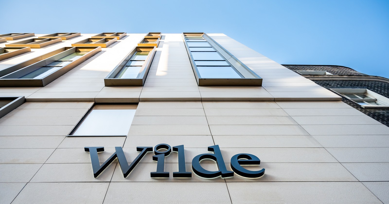 Modern building facade with large windows and the word "Wilde" in bold letters.