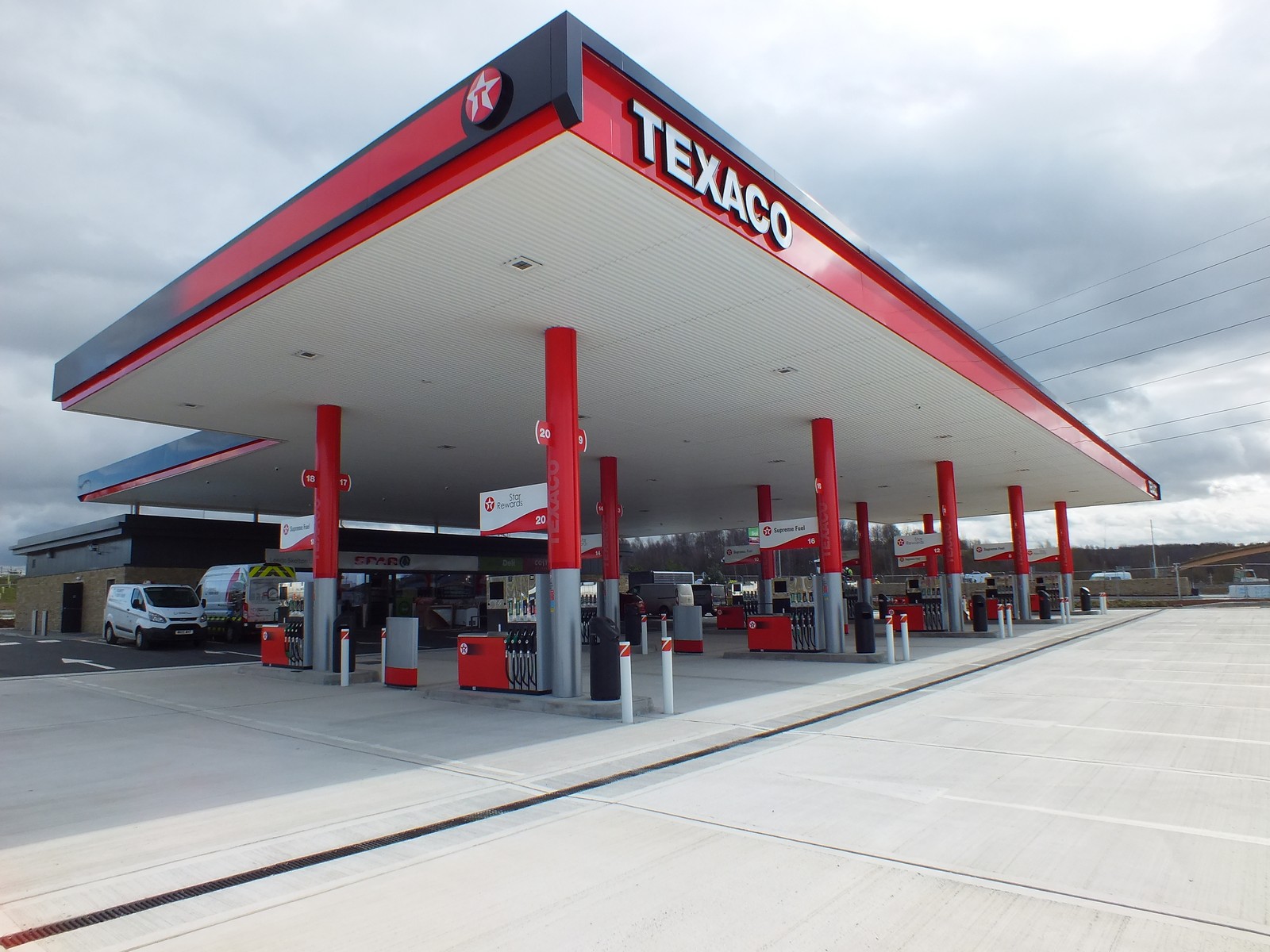 A Texaco gas station with multiple fuel pumps and a large canopy under a cloudy sky.