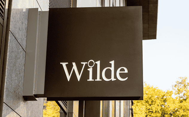 A black sign with the word "Wilde" in white letters is mounted on a building.