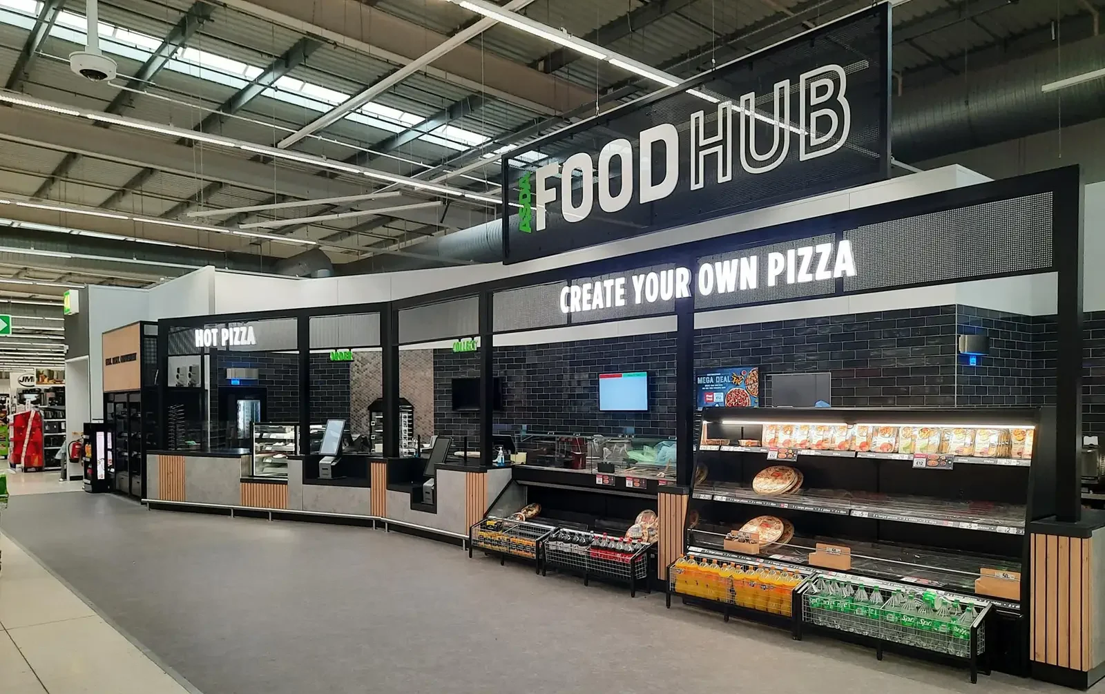Supermarket food hub with "Create Your Own Pizza" and "Hot Pizza" sections, shelves stocked with items.