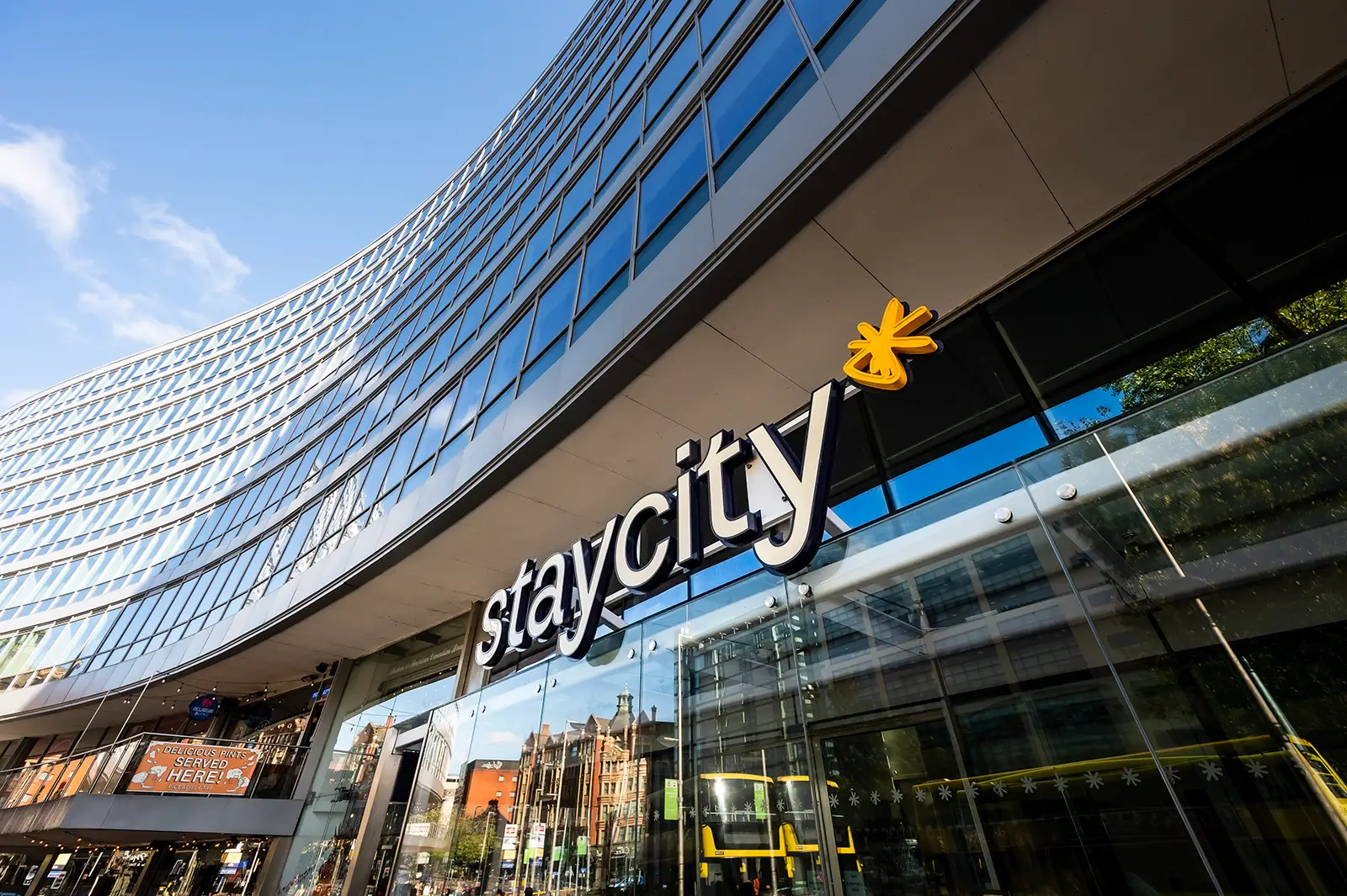 Curved modern building with large glass windows and "staycity" sign in bold letters.
