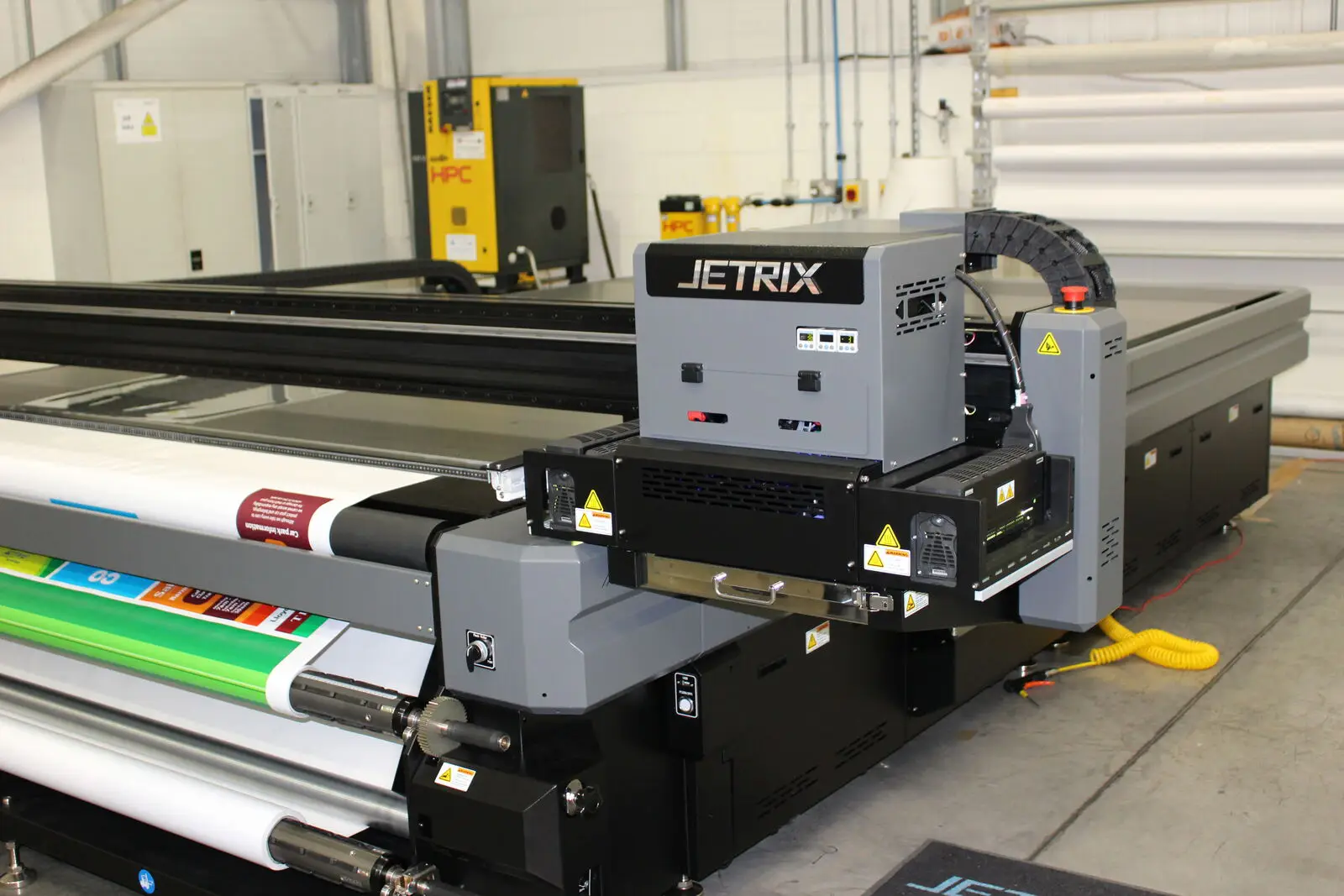 Large industrial printer with "JETRIX" branding, printing colorful material in a factory setting.