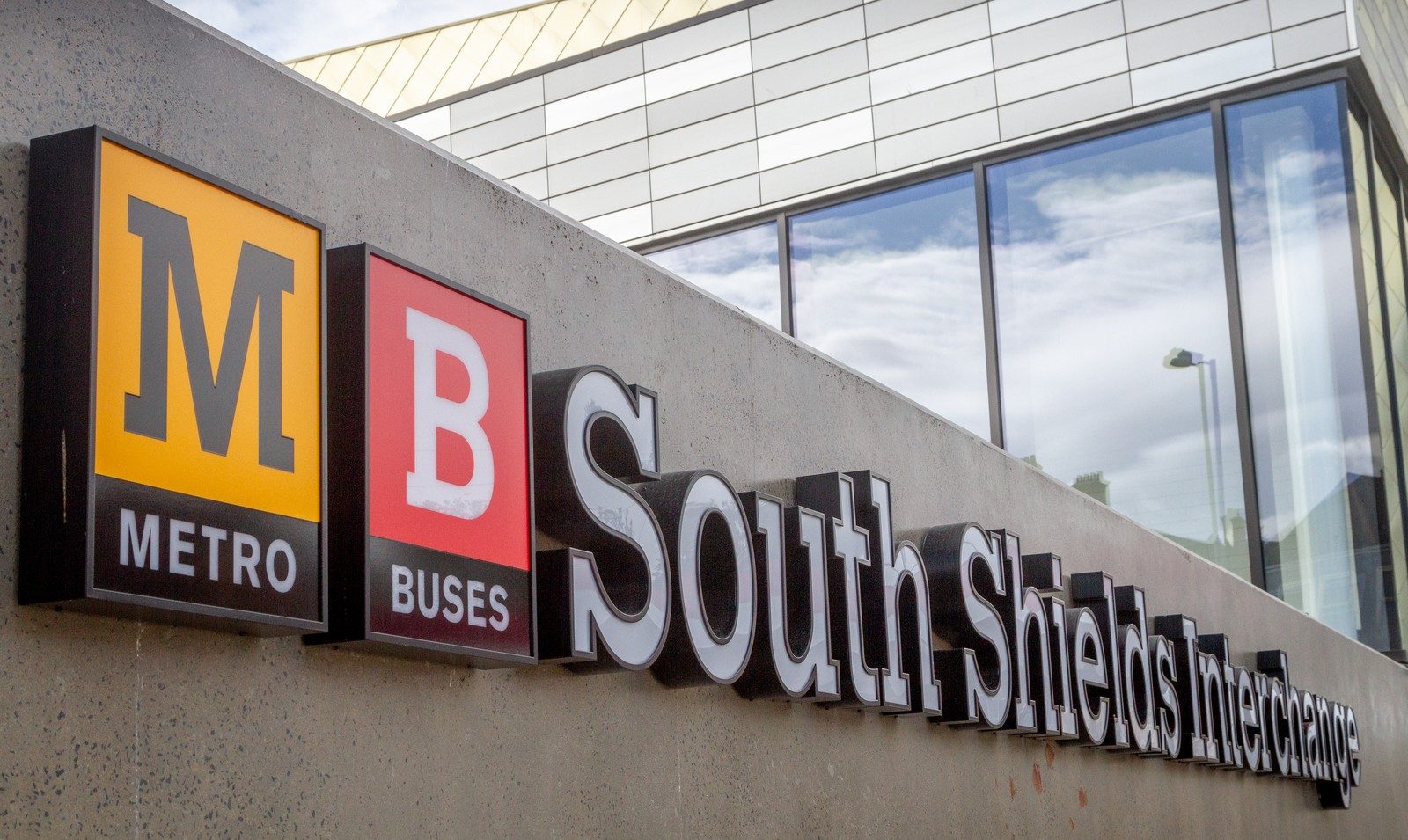 Sign for South Shields Interchange with Metro and Buses logos on a concrete wall.