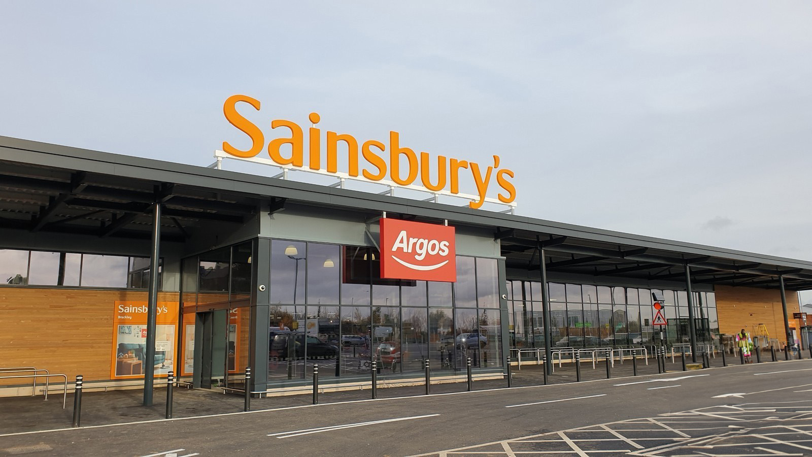 Large Sainsbury's store with an Argos sign, glass windows, and a parking lot in front.