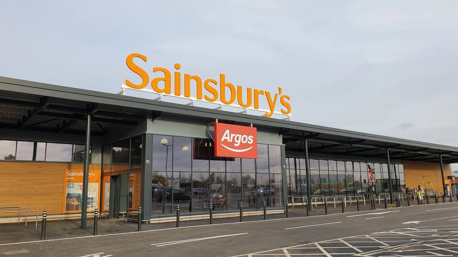 Large Sainsbury's store with an Argos sign, glass windows, and a parking lot in front.