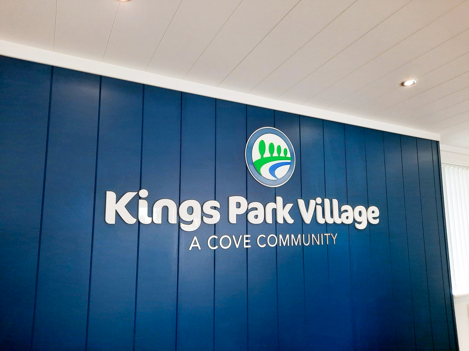 Blue wall with "Kings Park Village A Cove Community" and a circular logo above the text.