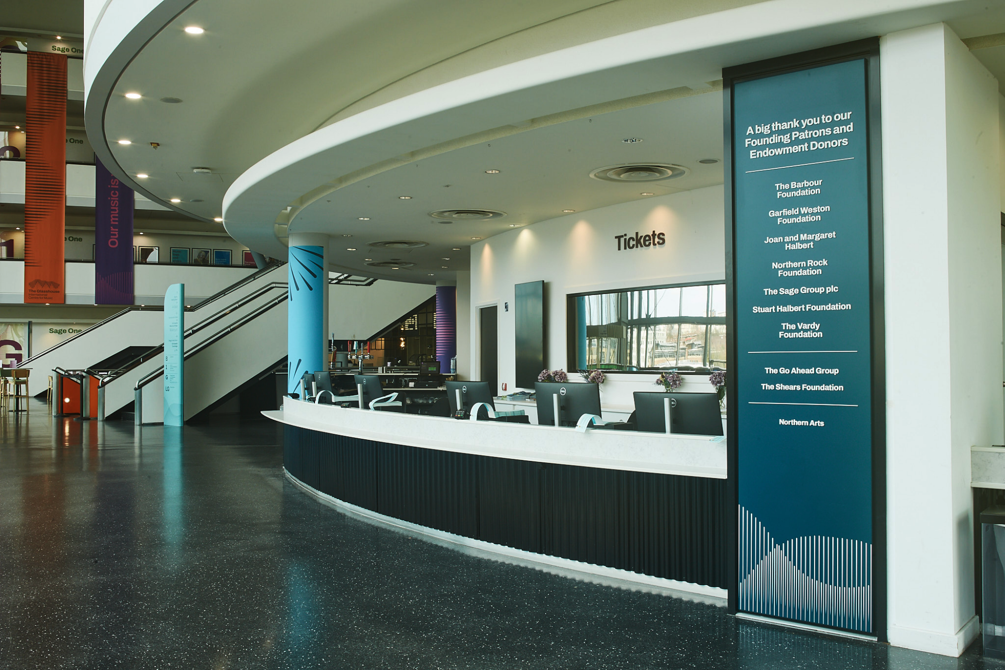 A modern ticket counter with a curved design and digital display in a spacious lobby.