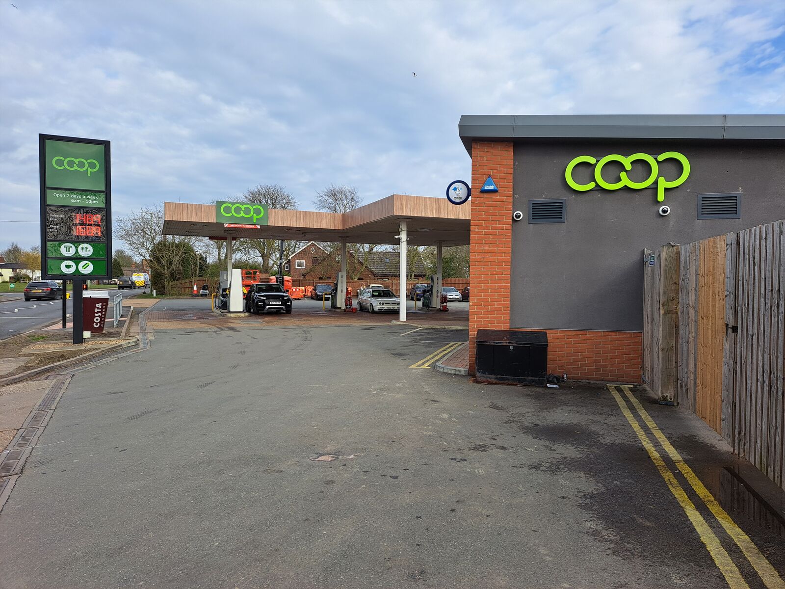 A Coop gas station with a convenience store and several cars parked under the canopy.