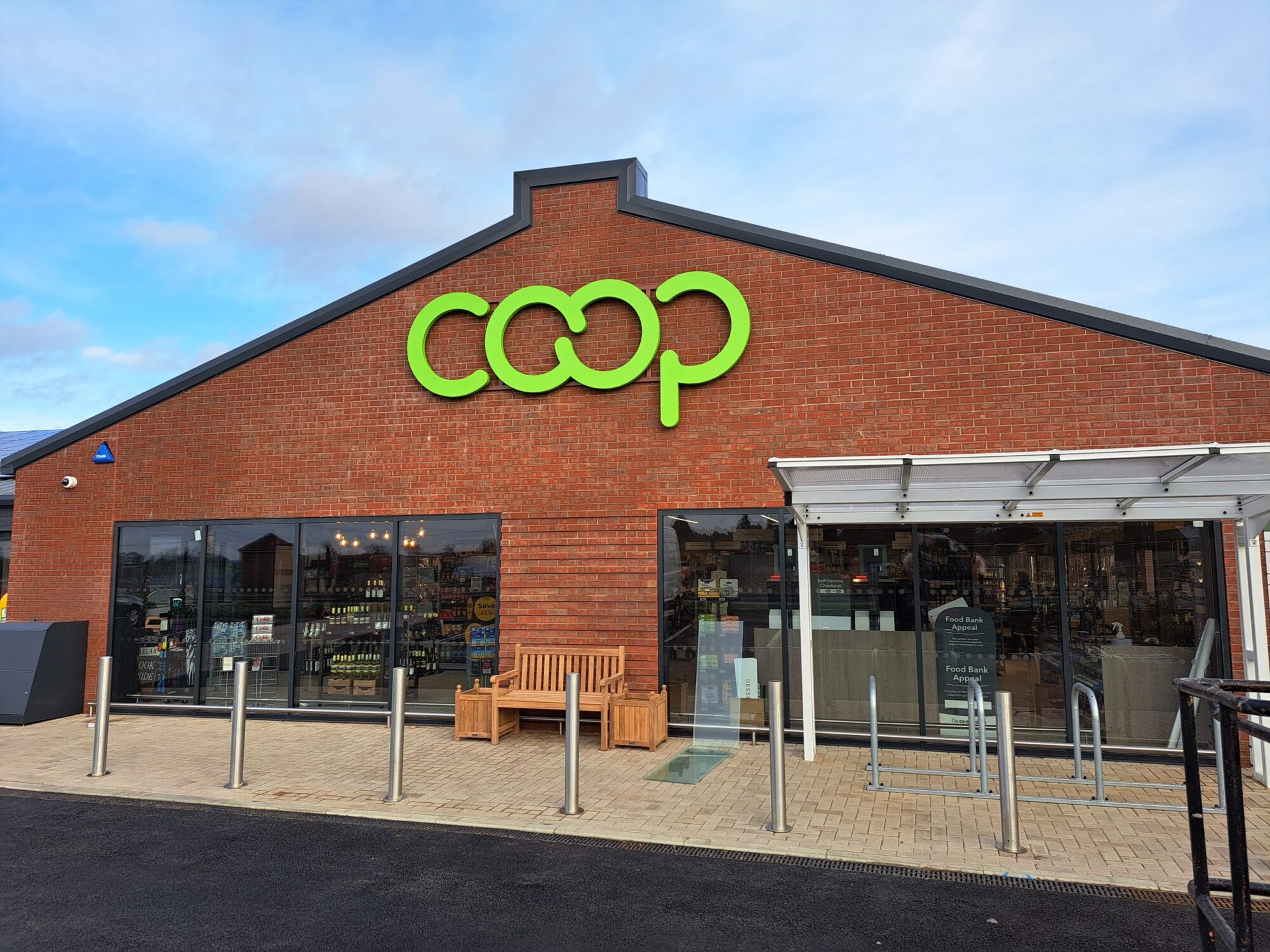 A brick Coop store with large windows and a green logo on the facade.