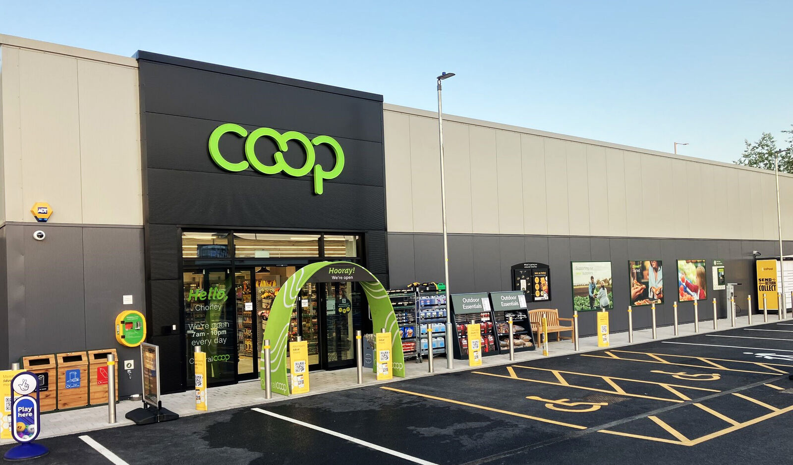 Coop store exterior with green signage, parking spaces, and promotional displays near the entrance.
