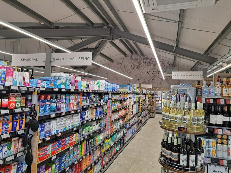 A supermarket aisle with health products, cards, magazines, and a wine display.