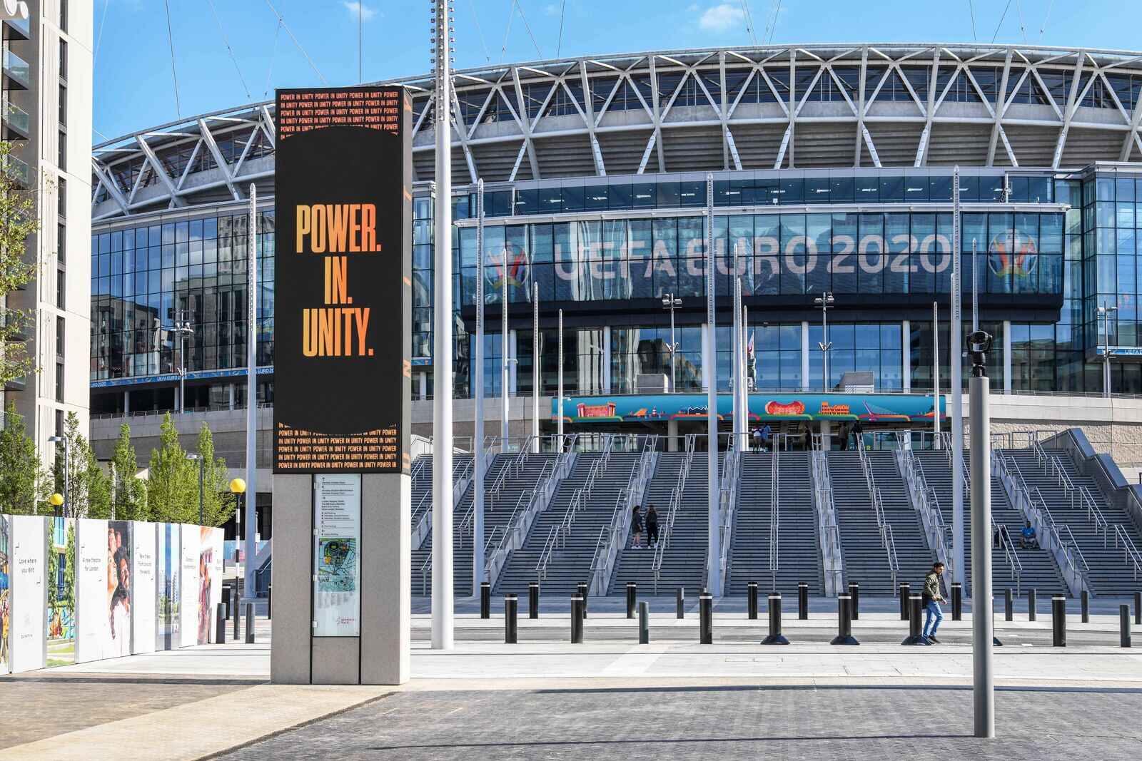 Stadium entrance with "Power in Unity" sign and steps leading up to glass facade.