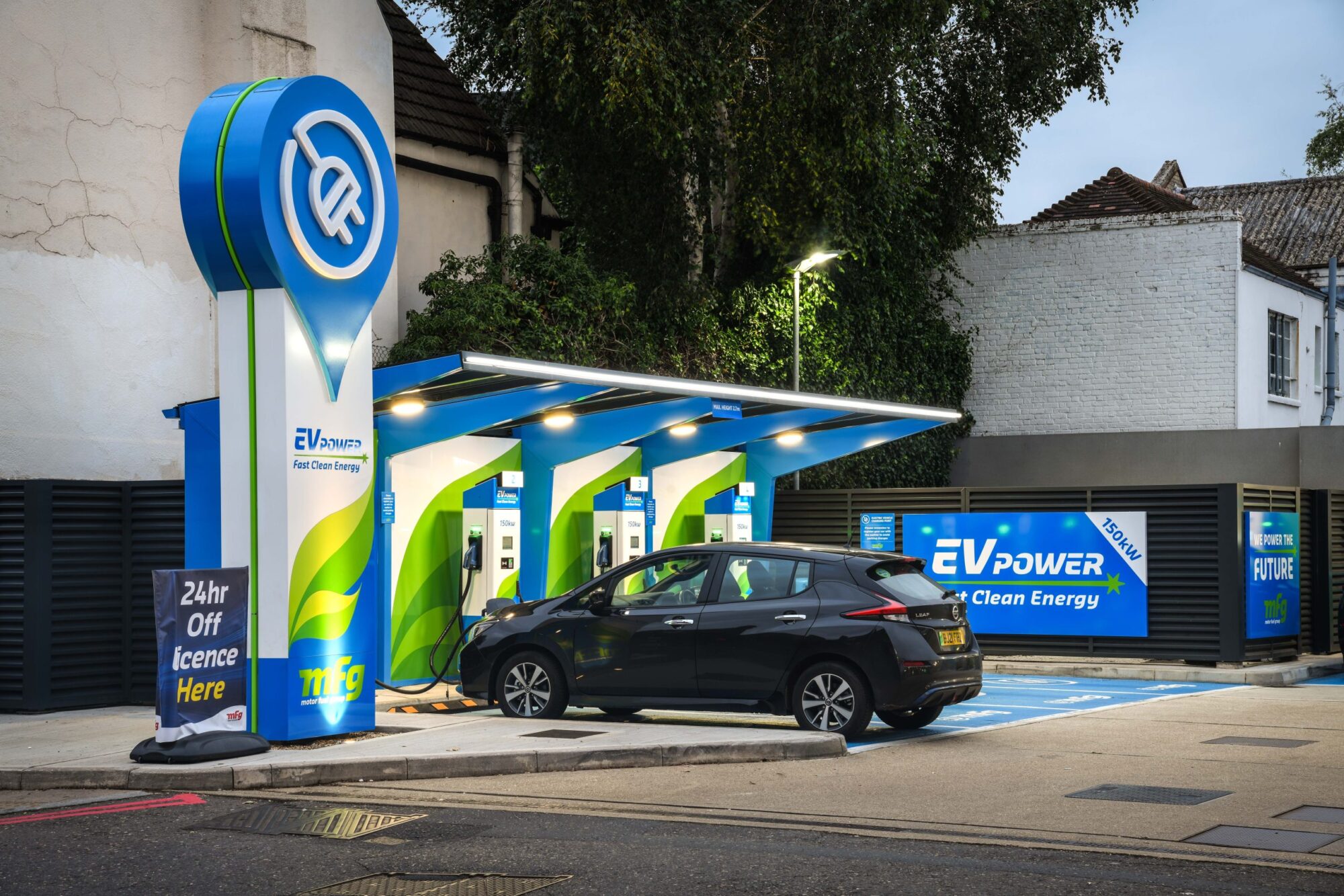 Electric car charging at a modern EV charging station with blue and green branding.