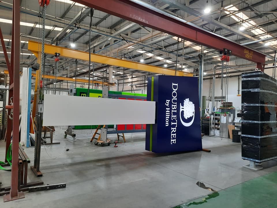 Large DoubleTree by Hilton sign hanging in an industrial warehouse with machinery and equipment.