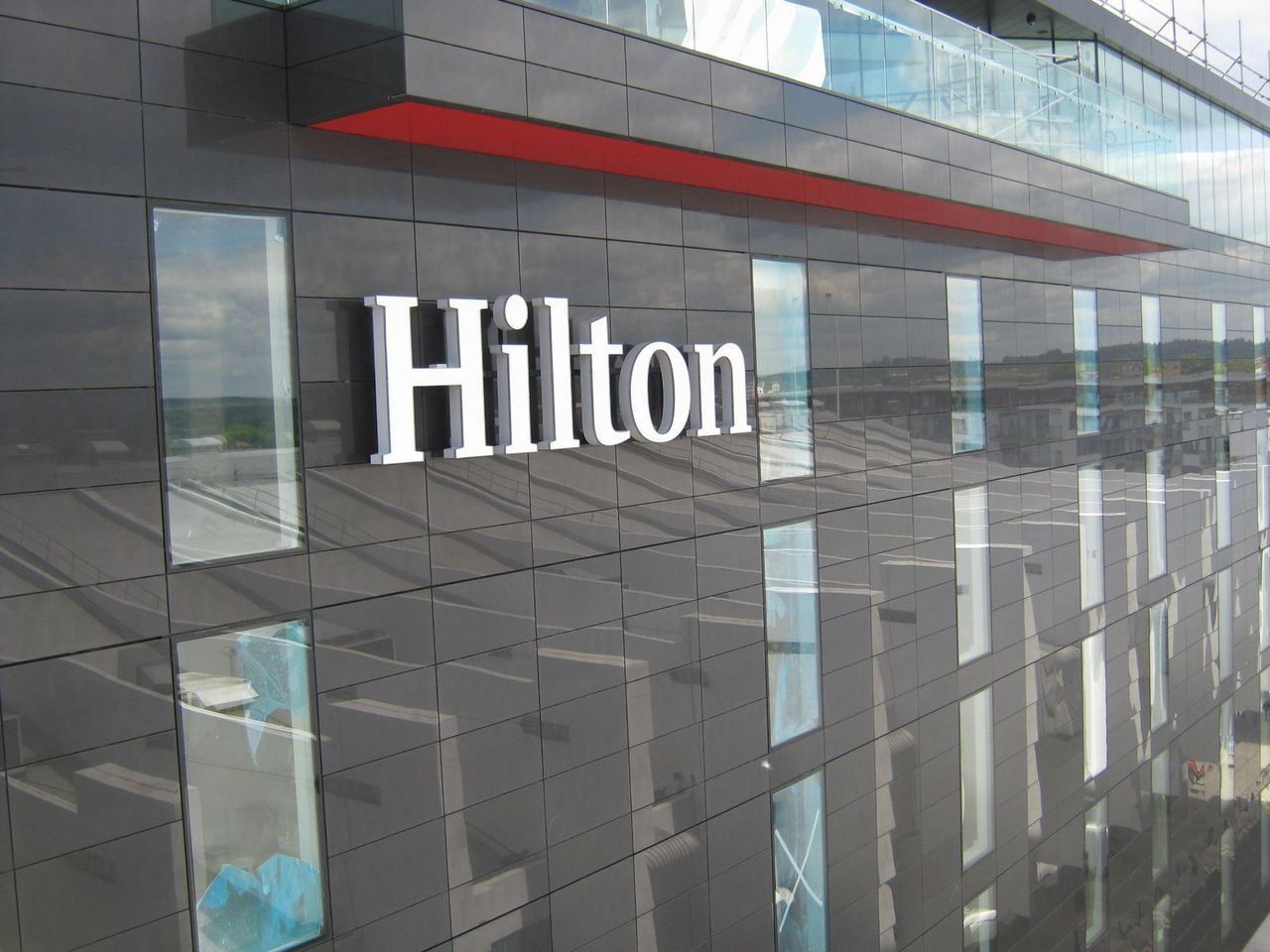The exterior of a modern building with "Hilton" in large white letters on a dark facade.