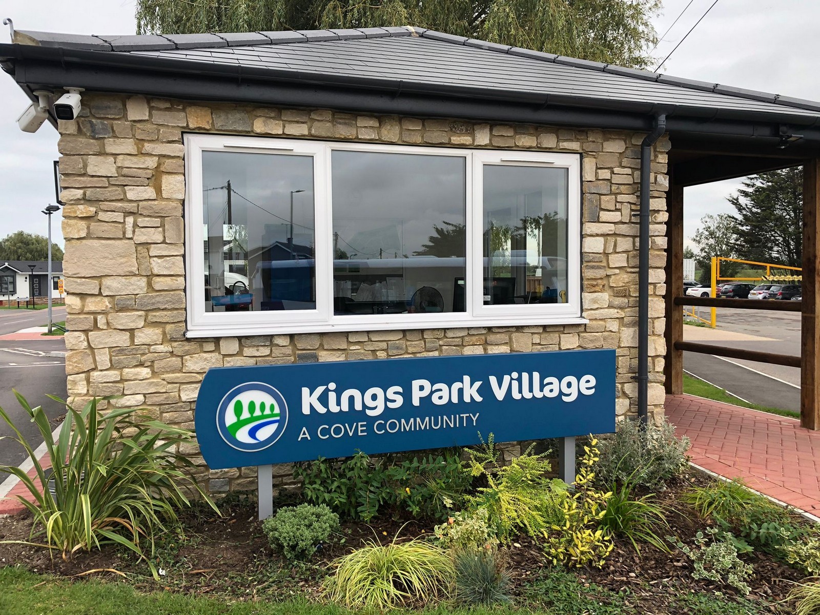 Stone building with large windows and a sign reading "Kings Park Village A Cove Community.