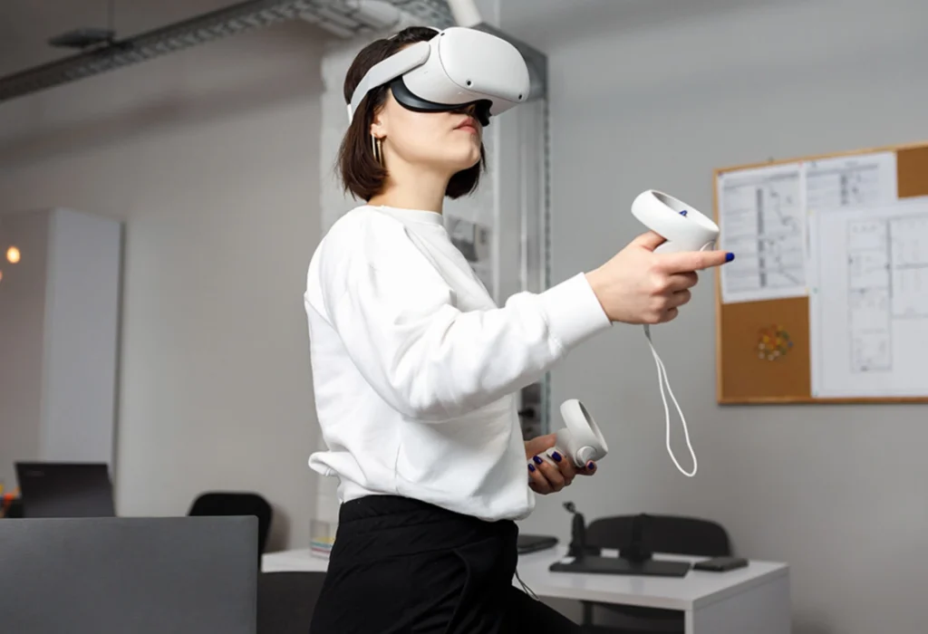 Person wearing a VR headset and holding controllers in a modern office setting.