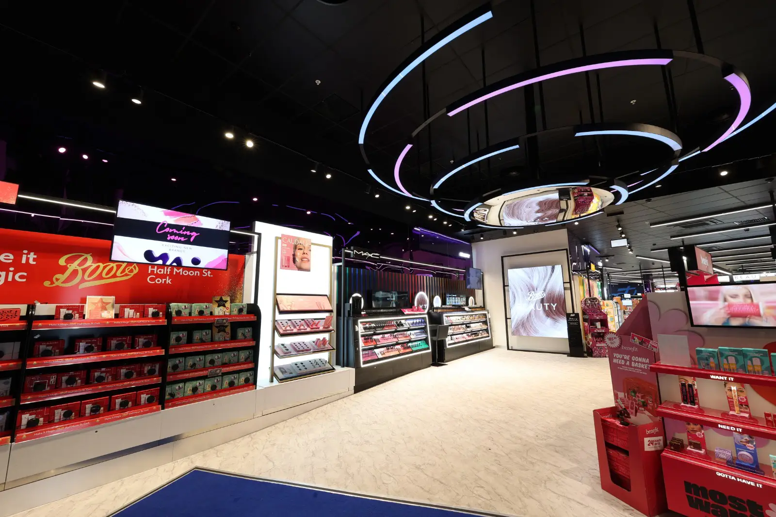 Modern retail store interior with illuminated displays, colorful shelves, and circular ceiling lights.