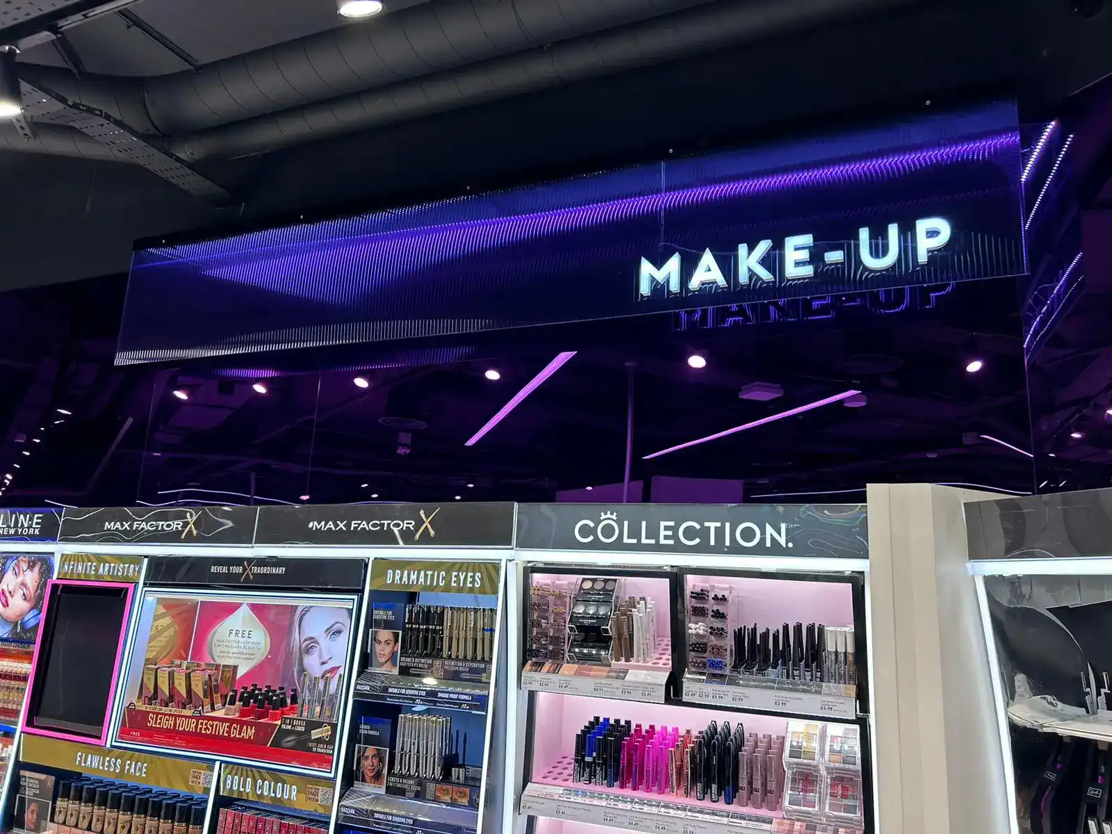 A makeup store section with illuminated "MAKE-UP" sign and various cosmetic products displayed.