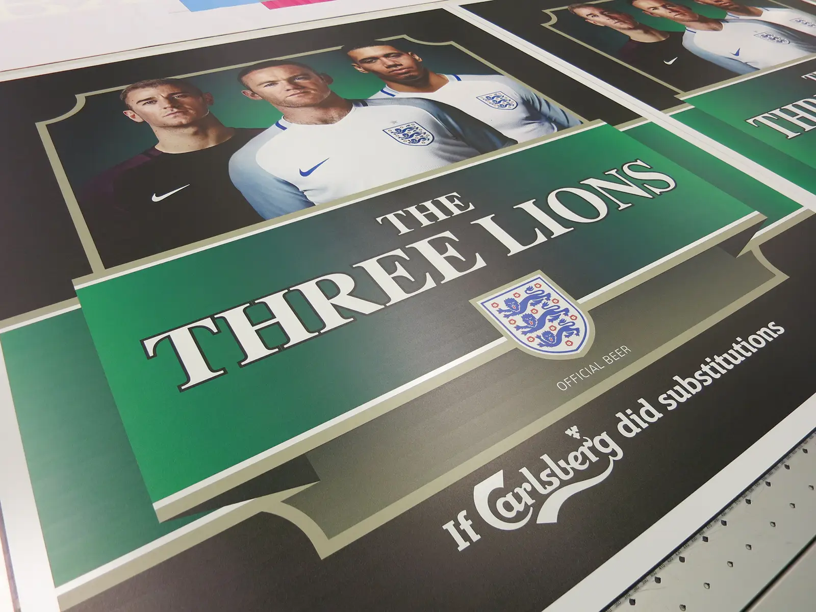A poster featuring four soccer players with "The Three Lions" and Carlsberg branding.