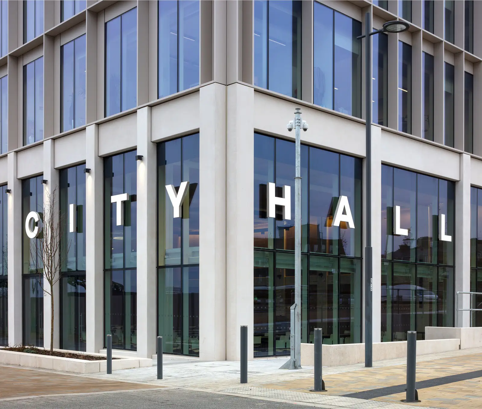 Modern building with large windows and "CITY HALL" in bold white letters on the facade.