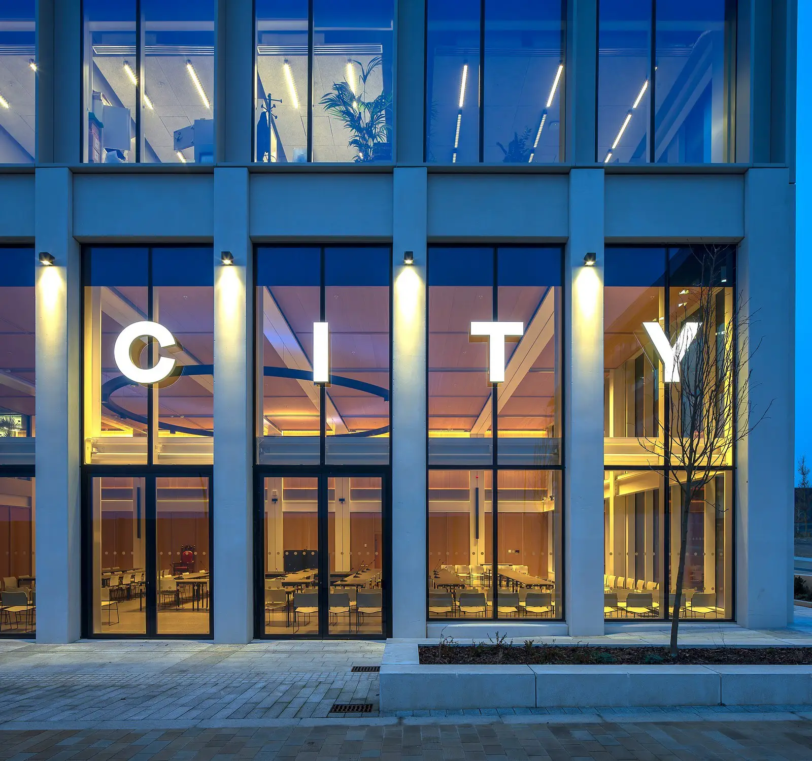 Modern building facade with large windows and the word "CITY" illuminated in white letters.