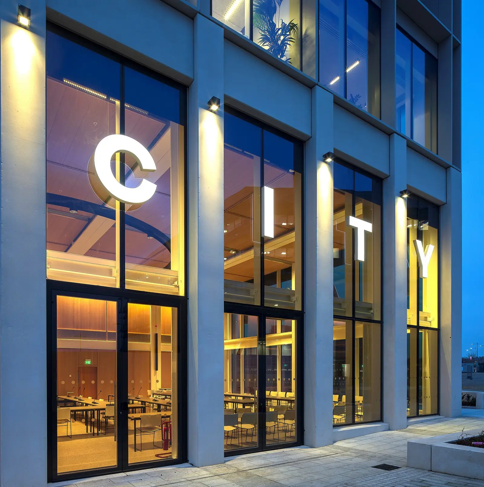 Large glass windows display the word "CITY" in illuminated letters on a modern building.