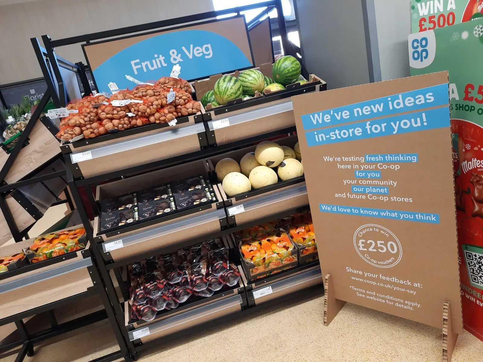 Display of fruits and vegetables with a sign about new store ideas and feedback request.
