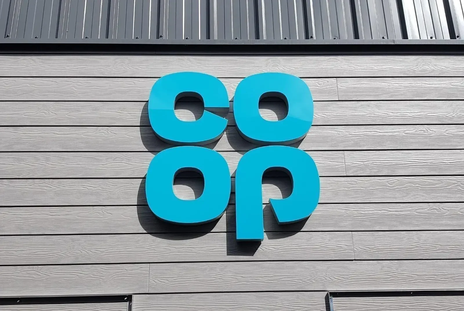 Blue "co-op" logo on a gray wooden building facade.