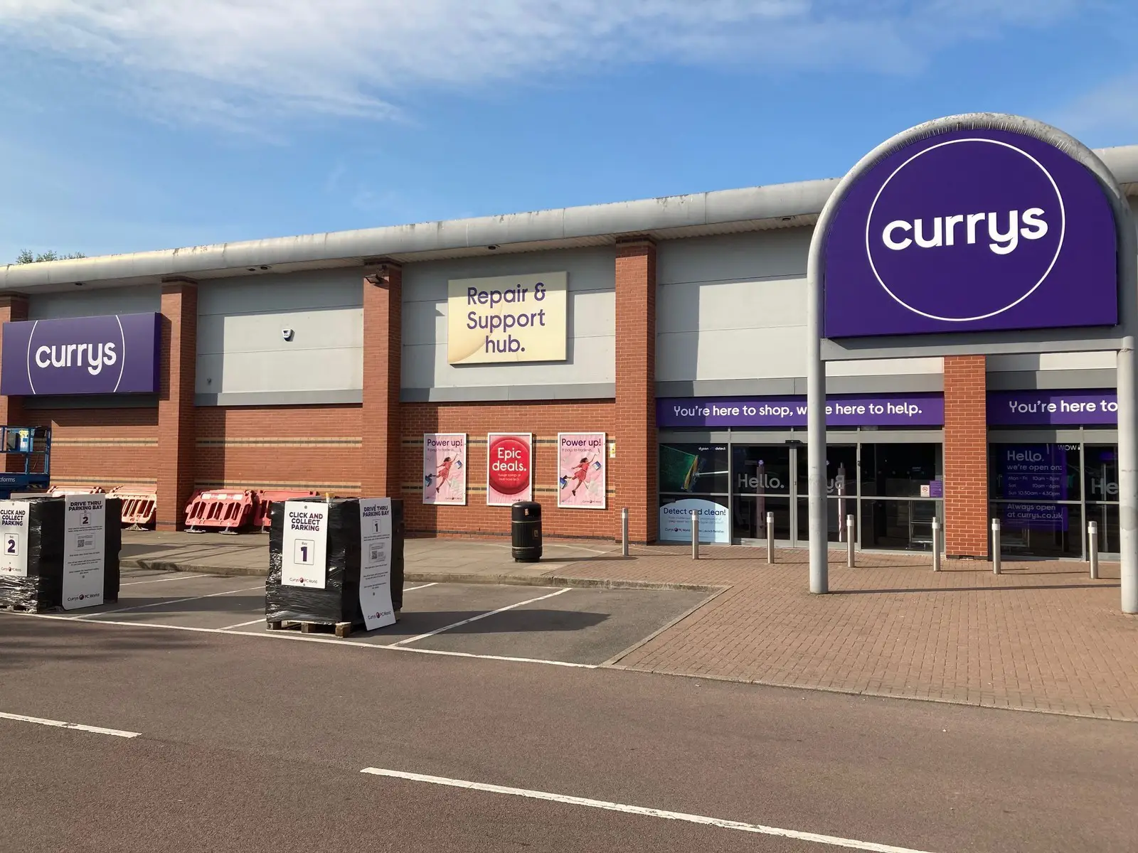 A Currys store with a Repair & Support hub sign and pallets outside.
