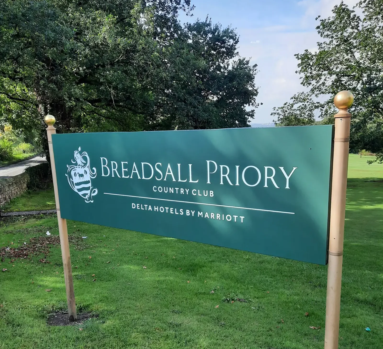 Green sign for Breadsall Priory Country Club, Delta Hotels by Marriott, on a grassy area.
