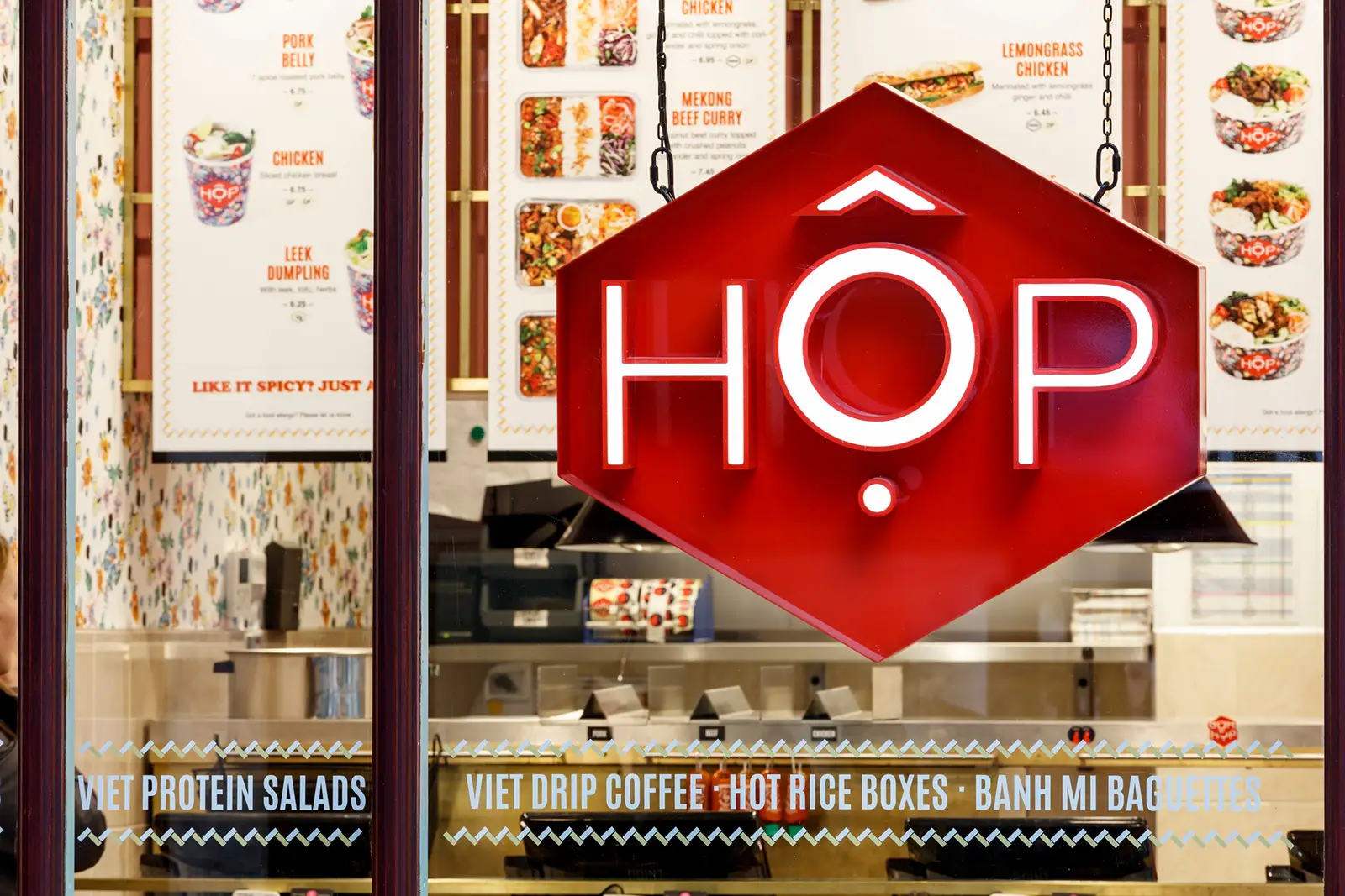 Red hexagonal sign with "HOP" in white letters, surrounded by menu boards and glass window.
