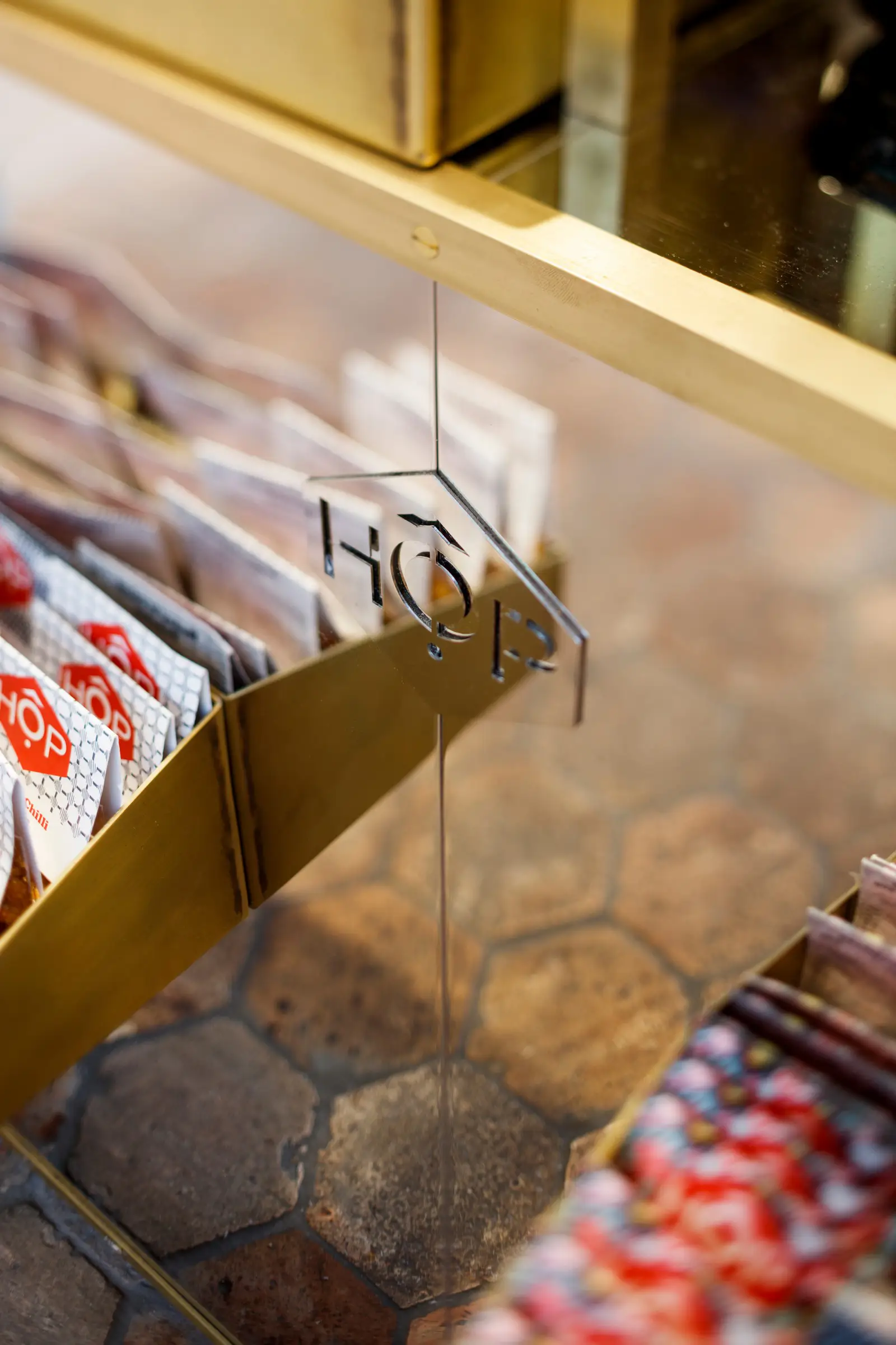 Packets of HOP candies displayed in a gold rack on a tiled floor.