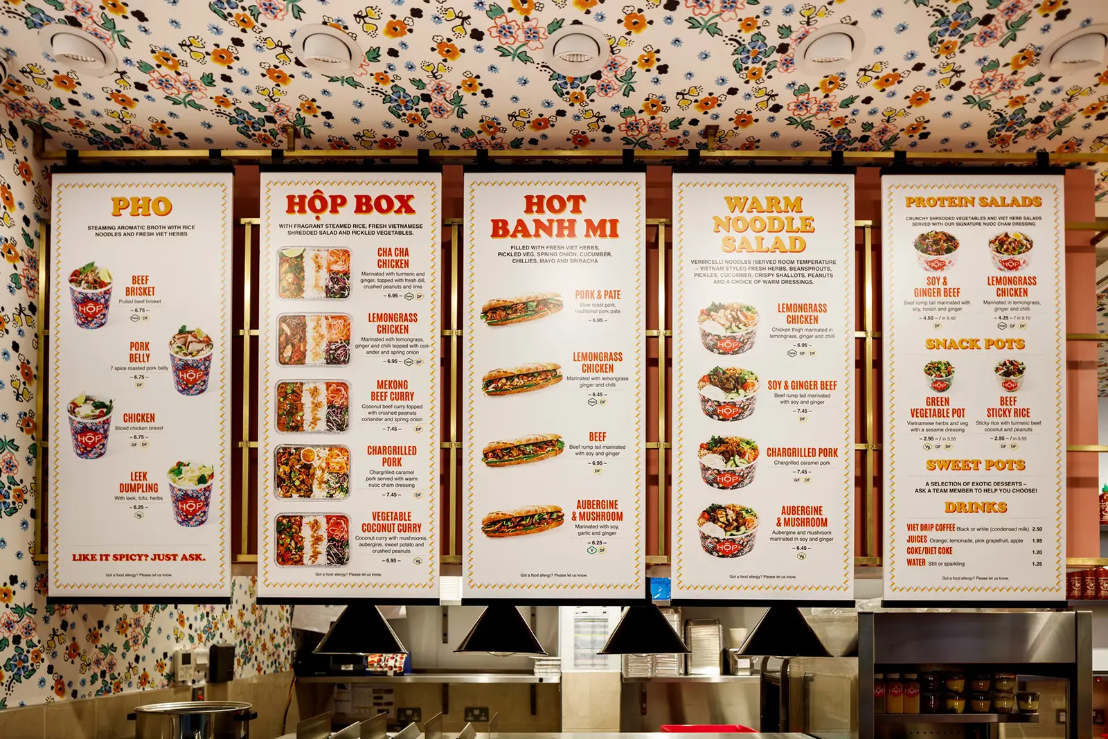 Five colorful menu boards with various food options hang above a restaurant counter.