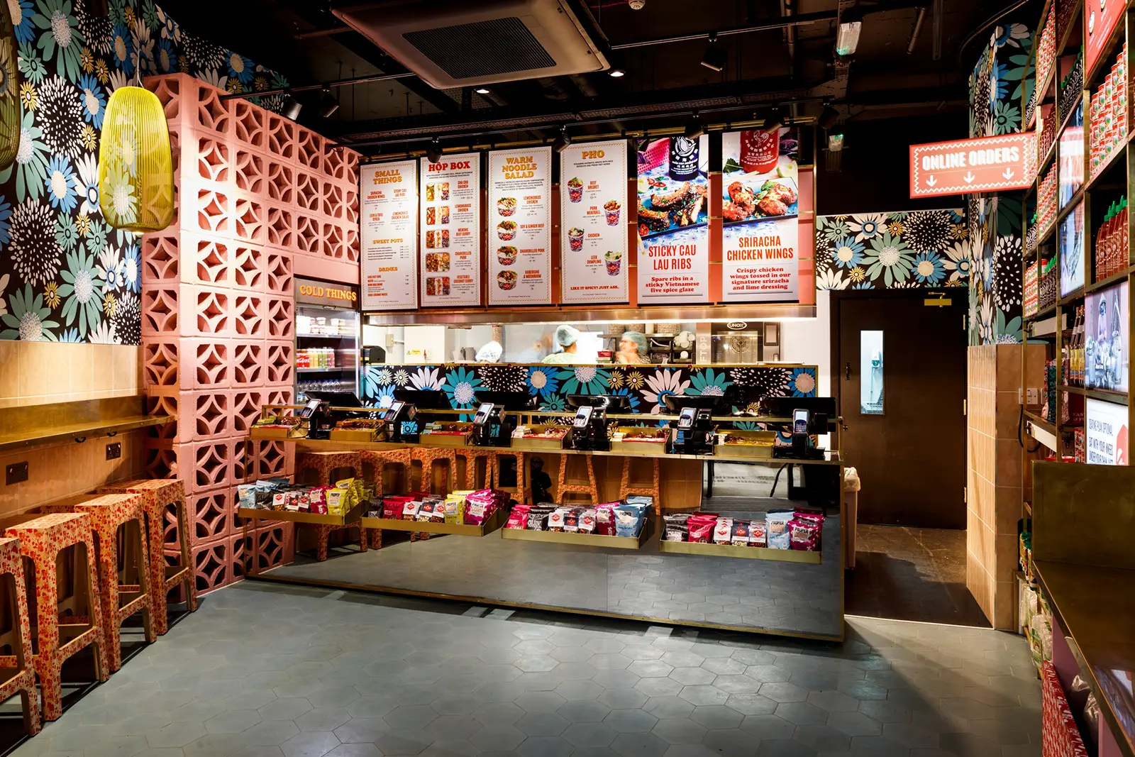 Colorful fast-food restaurant interior with floral wallpaper, menu boards, and wooden seating.