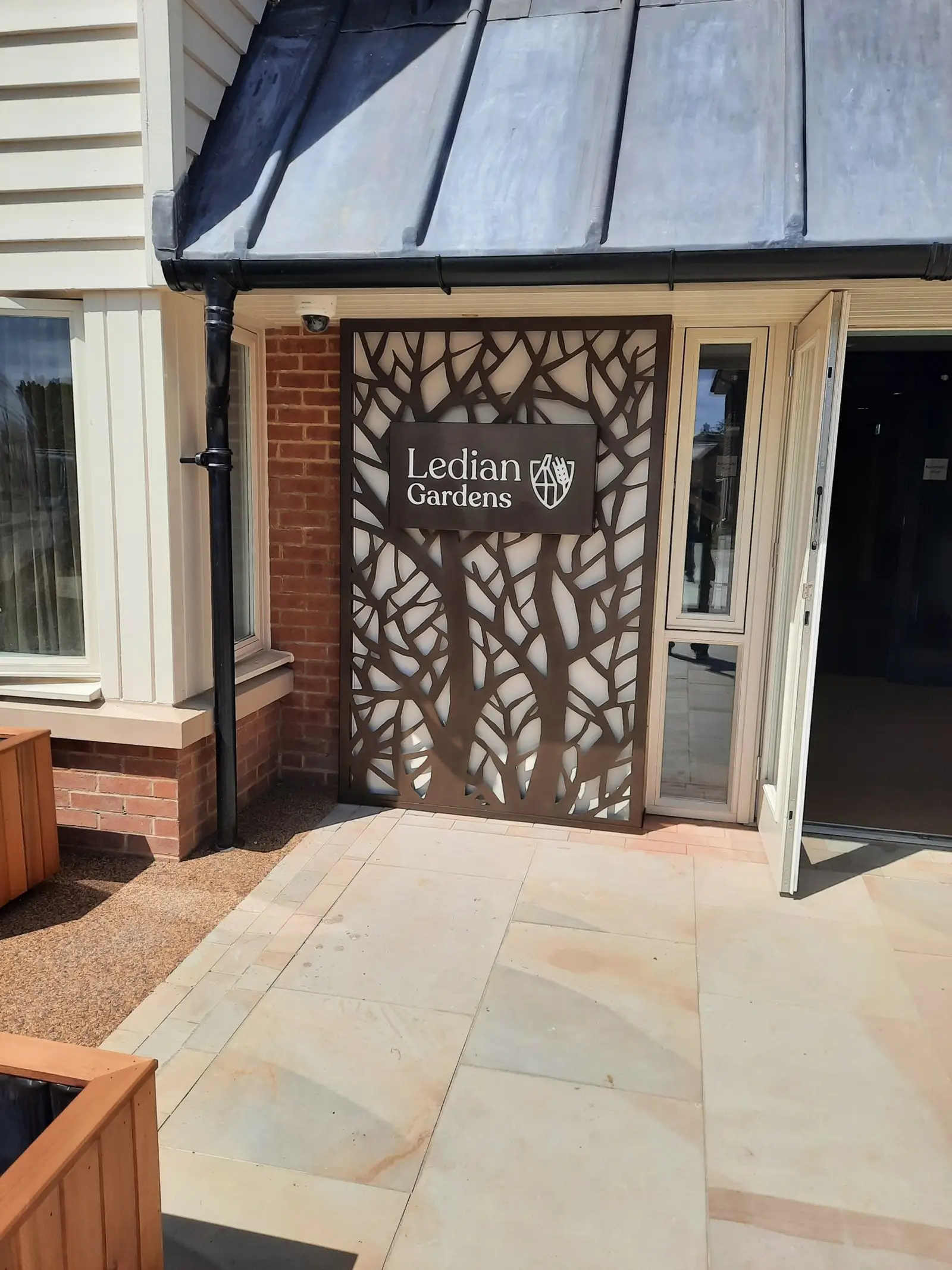 Entrance with a decorative metal panel and "Ledian Gardens" sign next to an open door.