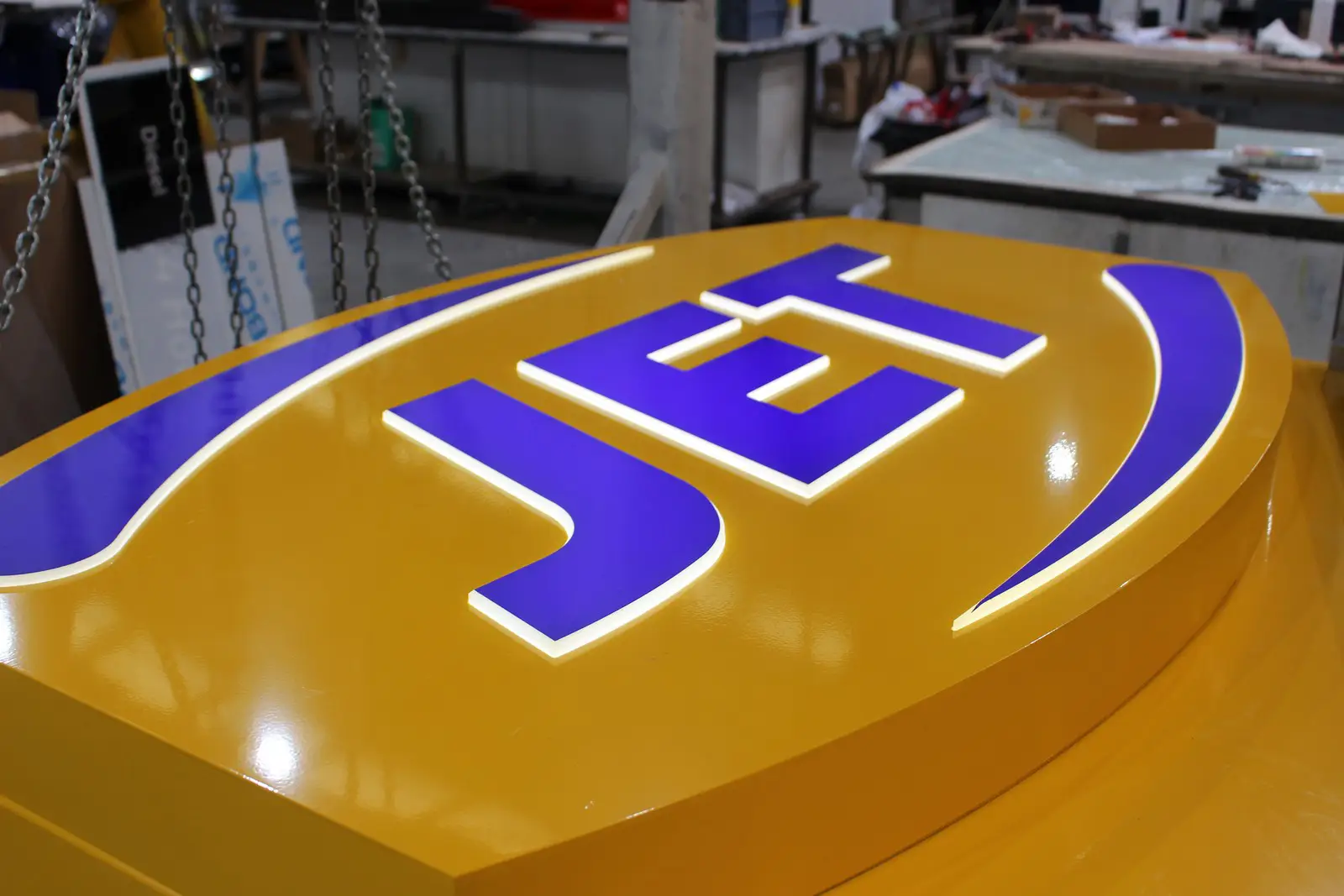 Illuminated yellow sign with the word "JET" in purple letters on a workshop table.