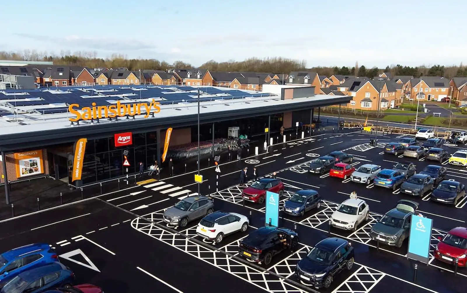 Aerial view of a Sainsbury's store with a parking lot and surrounding houses.