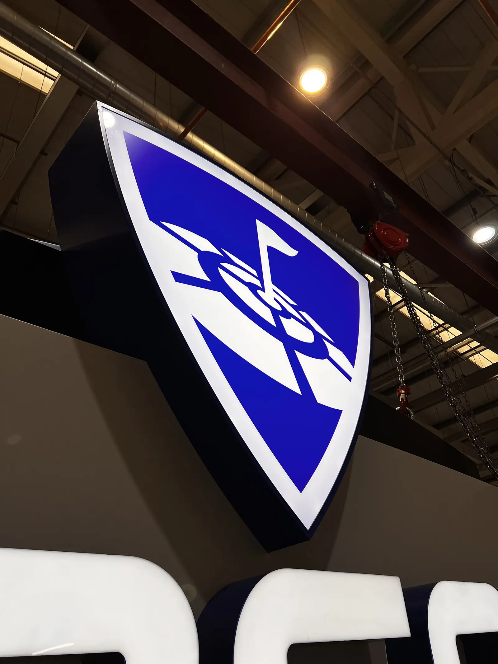 Blue and white shield-shaped sign with a stylized anchor and ship wheel design.