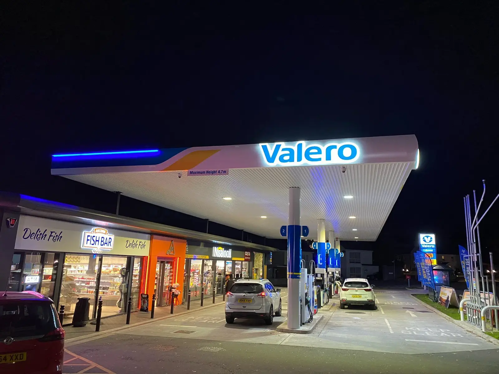 Valero gas station at night with cars parked and a lit convenience store.