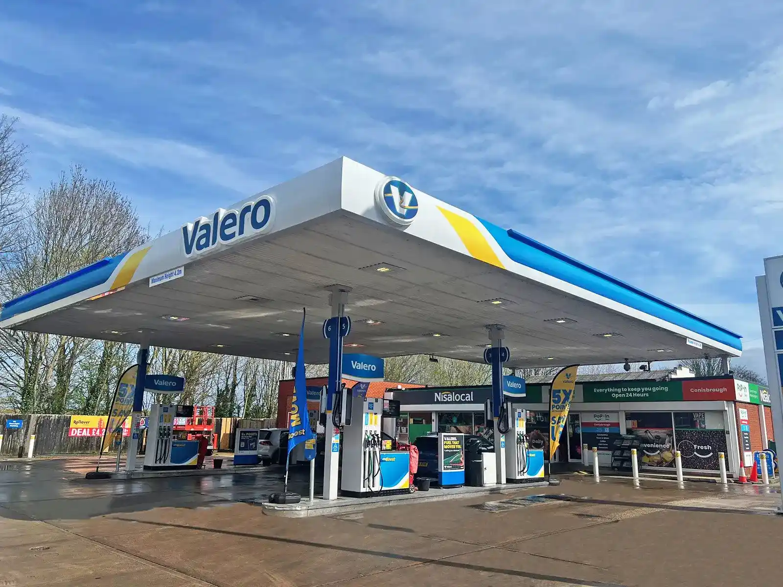 A Valero gas station with multiple fuel pumps and a convenience store under a blue sky.