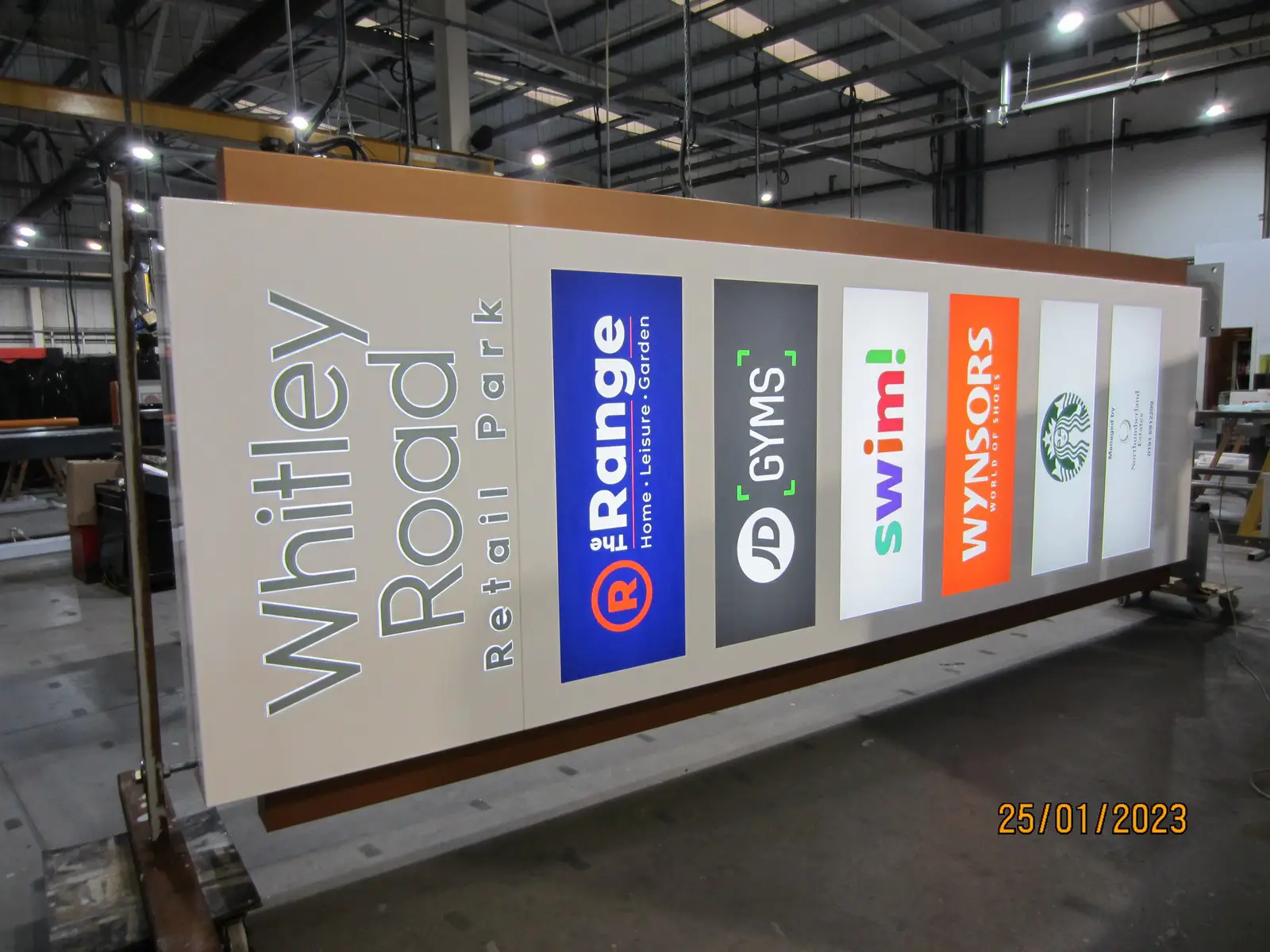 Large retail park sign with logos for The Range, JD Gyms, Swim!, Wynsors, and Starbucks.