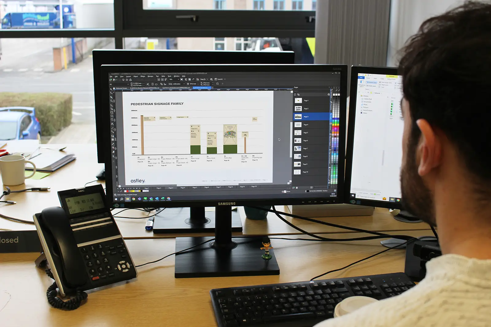 Person working at a desk with dual monitors displaying a presentation and a spreadsheet.
