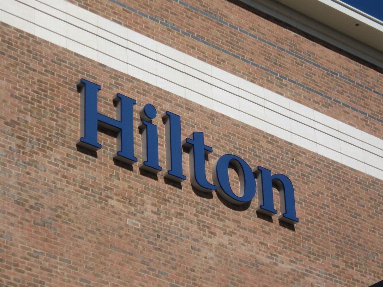 The word "Hilton" in blue letters on a brick building facade.