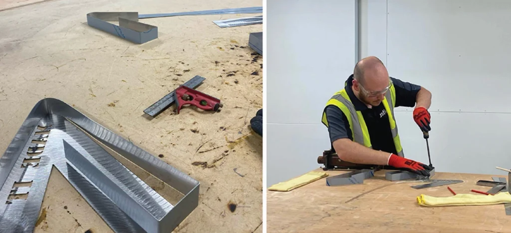 Metal letters and tools on a table; a person assembles a piece on the right.