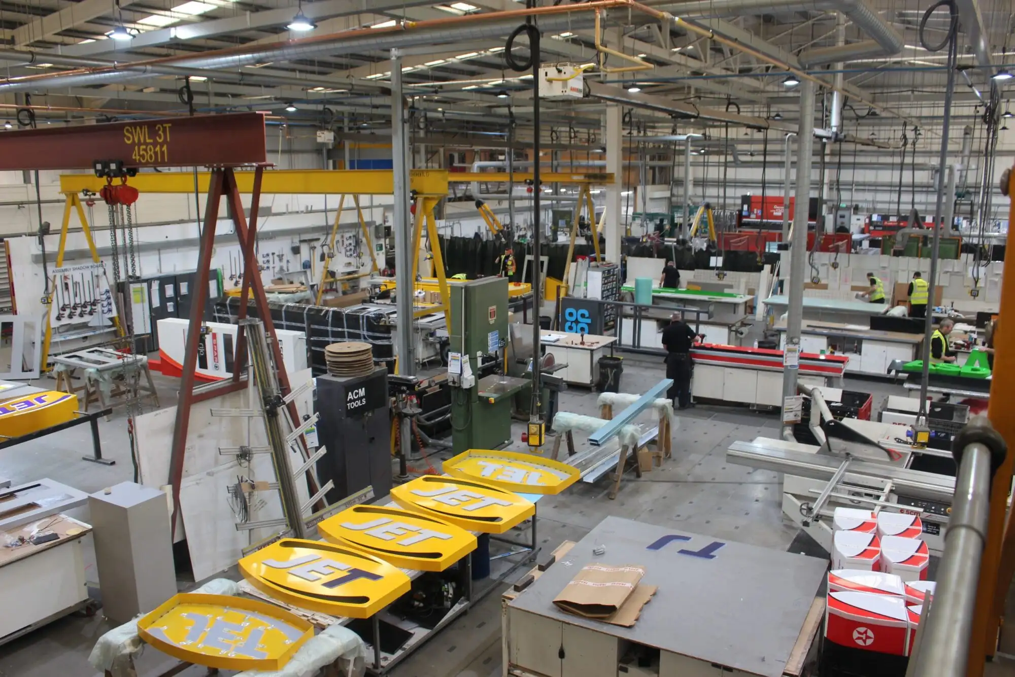Large industrial factory floor with machinery, workstations, and workers assembling various components.