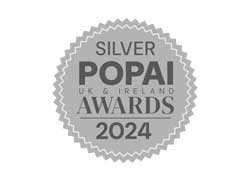 Silver POPAI UK & Ireland Awards 2024 emblem with a scalloped edge design.